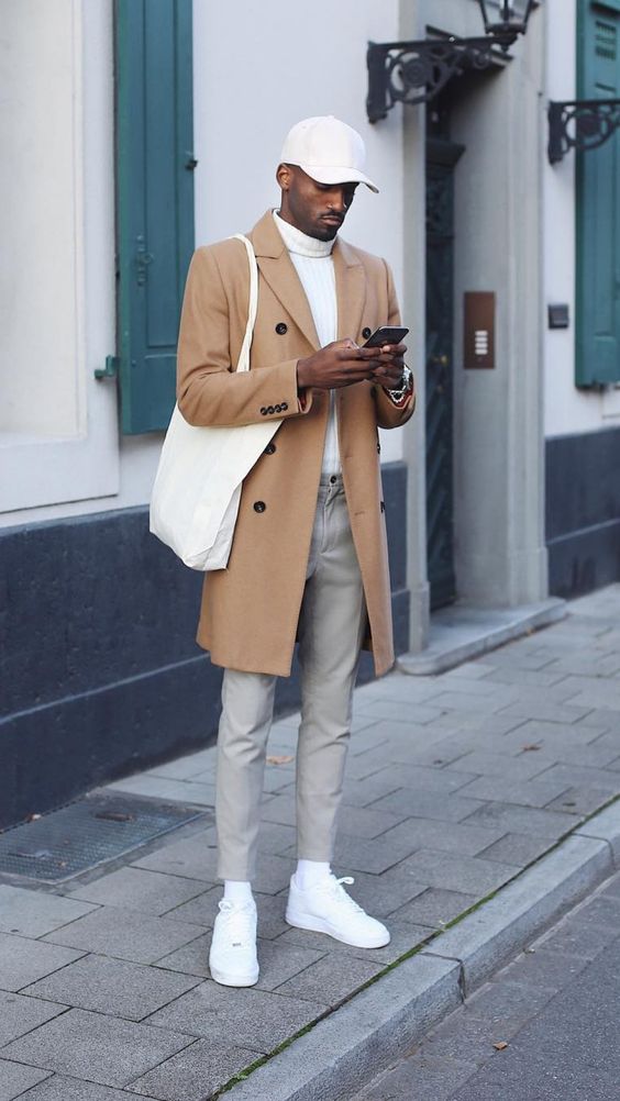A White Turtleneck Sweater, A Pair Of Grey Trousers, A Camel Trench Coat, White Sneakers And Socks, A Hat And A Tote
